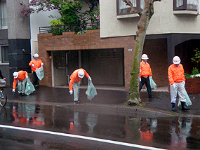 雨の中、ゴミ拾いをする職員たち