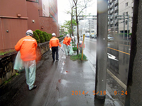 雨の中、ゴミ拾いをする職員たち