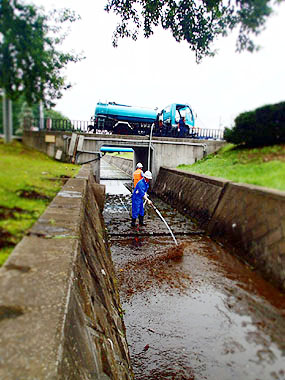 散水車を使い水路内を清掃する参加者たち